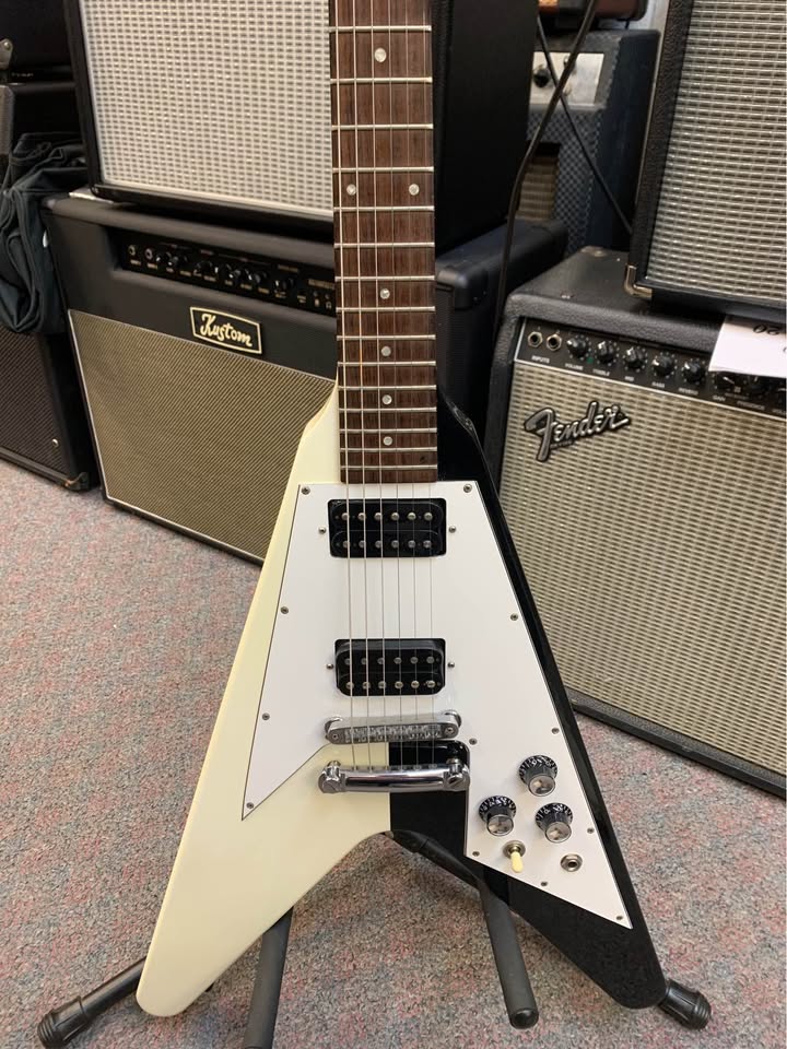 Close view of the second guitar body, white pickguard, pickups, bridge, and controls