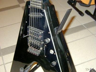 Close view of a black Gibson V90 Double showing its pickups, controls, and leg rest